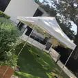 A 3mx6m Pop Up Marquee with a white roof set up on a lawn in front of a house.