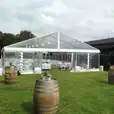A 6m x 39m white tent set up in a grassy area with wine barrels.