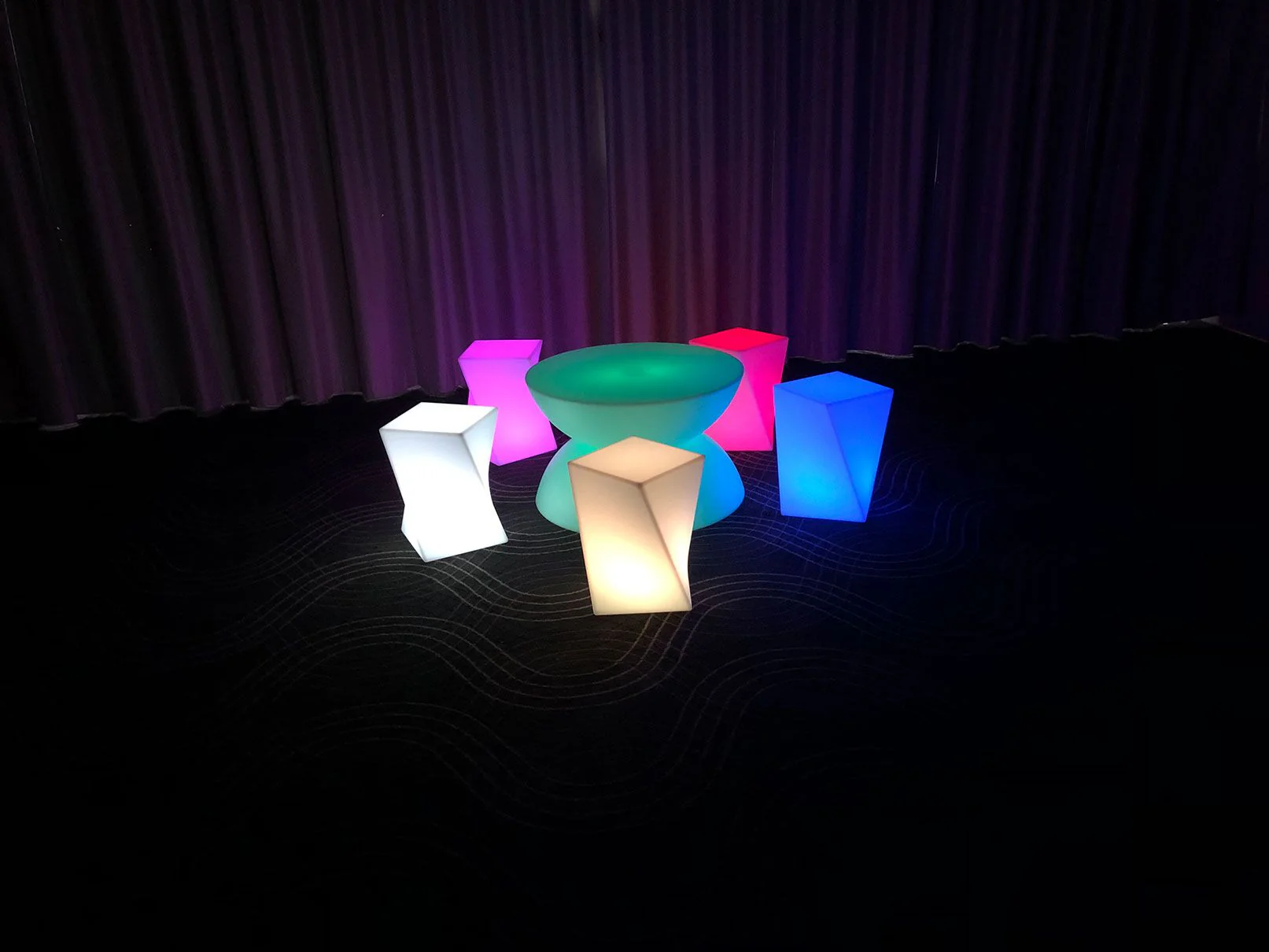 A group of vibrant stools in front of a curtain, available for hire.