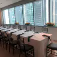 A table adorned with elegant black Tiffany chairs is set up in a room with a view of the city.