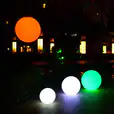 A group of glowing lighted balls in a park at night, available for Glow Sphere Hire.