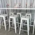 A white rectangular tapas table with stools underneath it