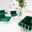 A white wire armchair lounge with green velvet cushions