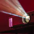 A 2500 Lumens digital projector with a red light shining on it available for hire.