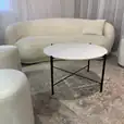 Black cross coffee with white top table next to a Ottoman stool