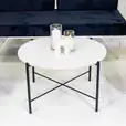 Black cross coffee table next to velvet lounge