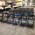 A row of black padded folding chairs in a lobby available for hire.
