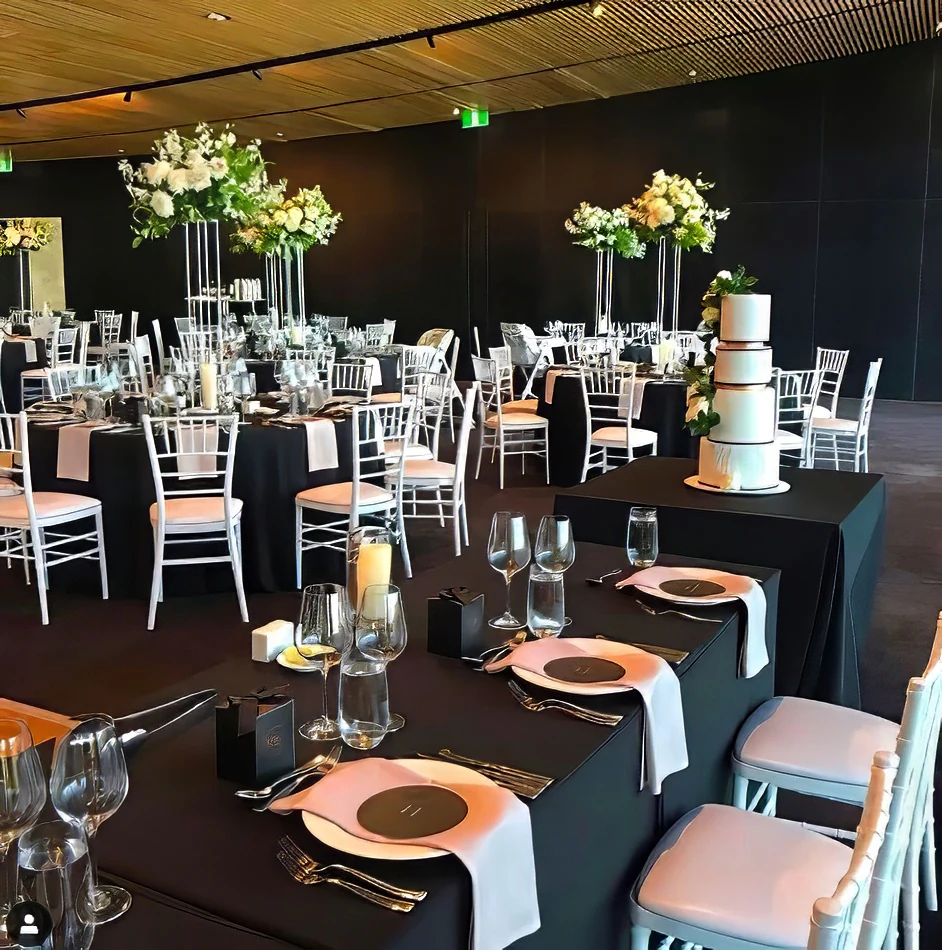 A black and white room with tables covered in black tablecloths.