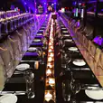 A long black tablecloth is set up on a standard trestle table in a dark room, with candles as the only source of light.