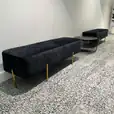 A black velvet lounge next to a black wire coffee table