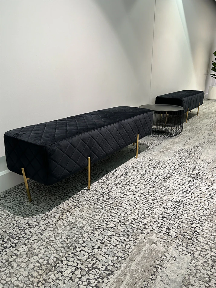A black velvet lounge next to a black wire coffee table