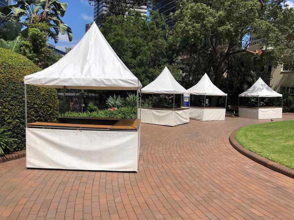A fete stall set up with white tents on a brick walkway.