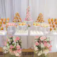 A dessert table adorned with cupcakes and flowers, featuring a Clear Acrylic Ghost Table.