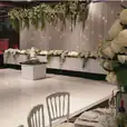 A glossy bridal wedding reception with white flowers and white tablecloths for hire.