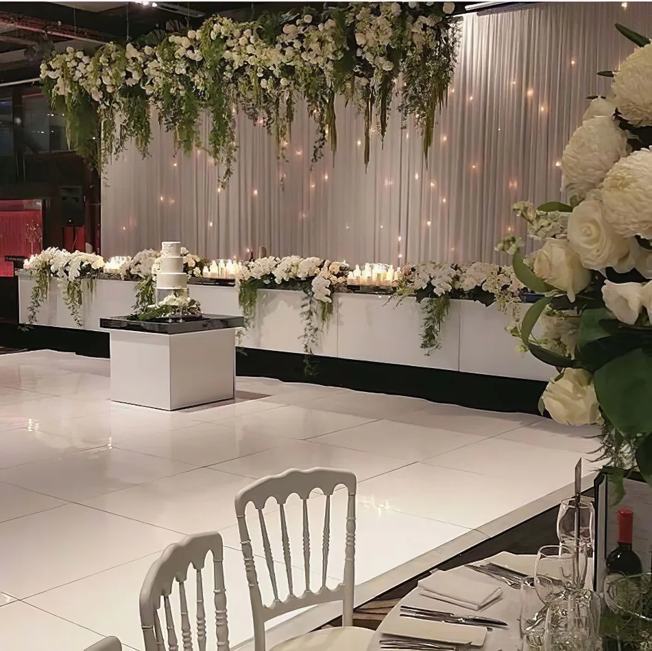 A glossy bridal wedding reception with white flowers and white tablecloths for hire.