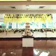 A glossy wedding cake adorns a beautifully decorated table in a spacious room.