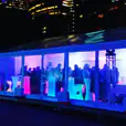 A large tent with people standing in front of it, illuminated by glowing pillars at night.