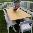 A white table with chairs in a grassy area, adorned with a gold hairpin banquet table with a timber top.