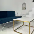 Gold rectangle a coffee table next to a blue velvet lounge