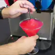 A person pouring *60 drinks* into a machine.