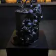 A black cake is on display on a black square plinth.