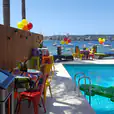 A lively pool party complete with a Jukebox & Karaoke Hire for added entertainment, where a table and chairs are conveniently placed near the water.