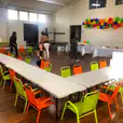 A room filled with tables and chairs for kids, adorned with colorful balloons.
