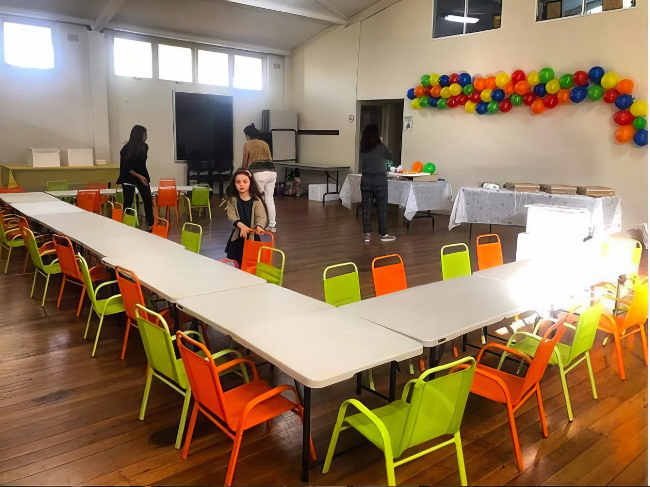 A room filled with tables and chairs for kids, adorned with colorful balloons.