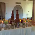 A large chocolate fountain is on a table in front of a mirror.