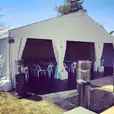 A white tent set up in a backyard, illuminated with LED floodlights hired for the occasion.