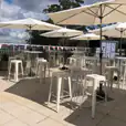 A white table and chairs on a patio with market umbrellas.