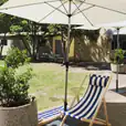 A blue and white striped lounge chair under a market umbrella.