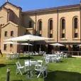 A large building with white tables and chairs in front of it, perfect for Market Umbrella Hire.