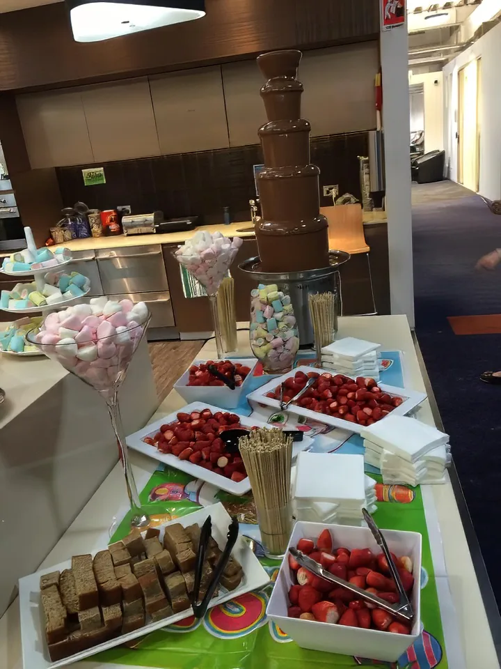 A chocolate bar with strawberries, marshmallows, and other desserts on a table.