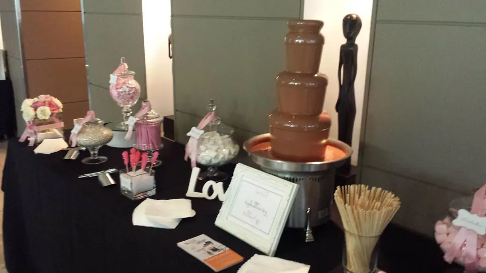 A table with a small commercial chocolate fountain and candy on it.