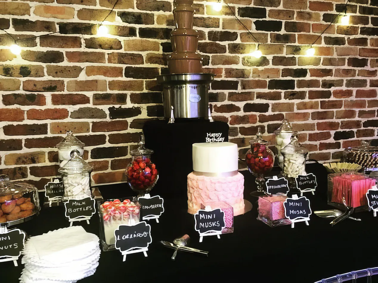 A dessert table featuring a medium commercial chocolate fountain.