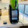 A green juice machine *sitting on a counter* in a kitchen.