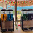 Two Slushie Machine drinks are sitting on a table in front of a window, offering a refreshing selection of 240 drinks.