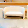 A white bouclé 2 seater sofa on a set of steps.