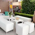 A patio with white furniture, including a white ottoman cube hire, and potted plants.