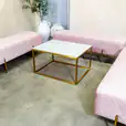 Three pink velvet ottoman benches with a coffee table in the middle