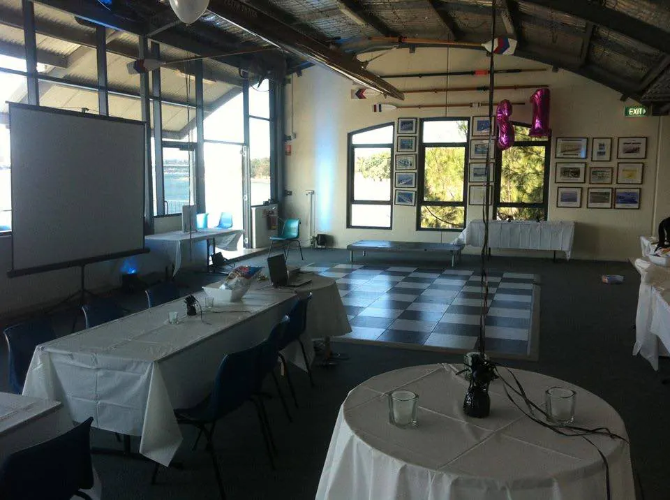 A room with tables and chairs set up for a party, including a projector screen hire (2m wide x 1.5m tall).