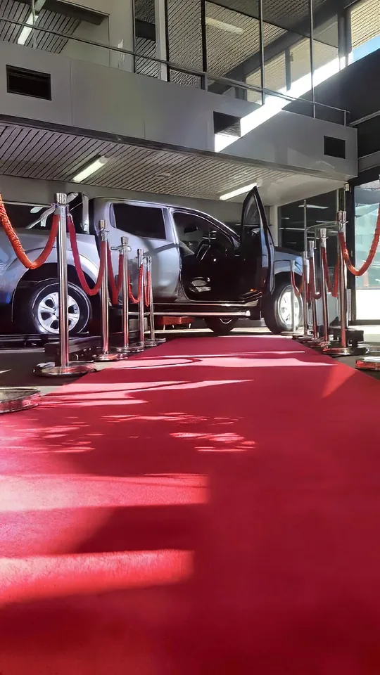 A car is parked on a red carpet in a parking lot, rented from Red Carpet Hire.