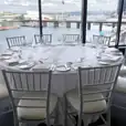 Round timber table hire with white chairs and a view of the city.