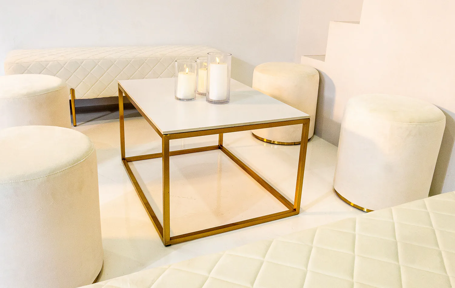 Four white ottoman stools next to a white coffee table