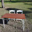 Two chairs and a table for hire in the grass.