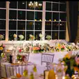 A table set up with flowers and candles in front of a window, enhanced with elegant silver Tiffany chairs.