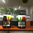 Two juice dispensers, including a Slushie Machine: Package 5 with *240 Drinks*, adorned with plants.