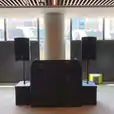 A room with two speakers on speaker stands in front of a large window available for hire.