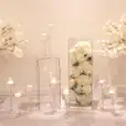 Clear vases with white flowers and candles in them.